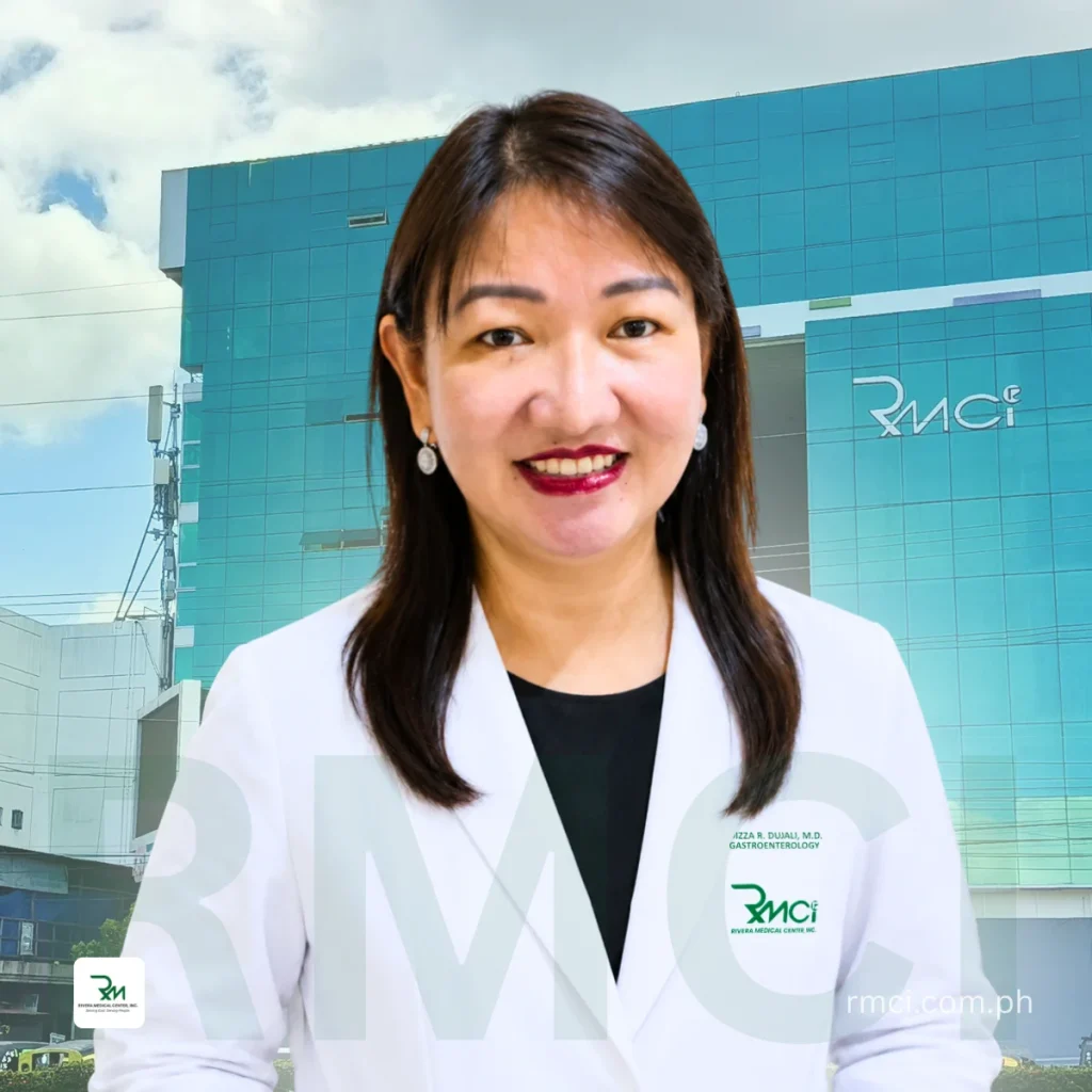 Smiling female doctor in a white coat outside a blue glass RMCI building with logo point of context clarity