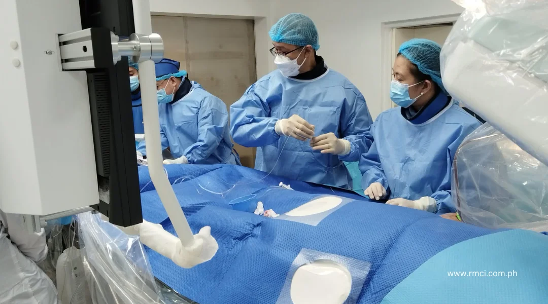 Surgical team in blue gowns and masks performing an operation beside a large imaging device over a patient covered in blue sterile drapes.
